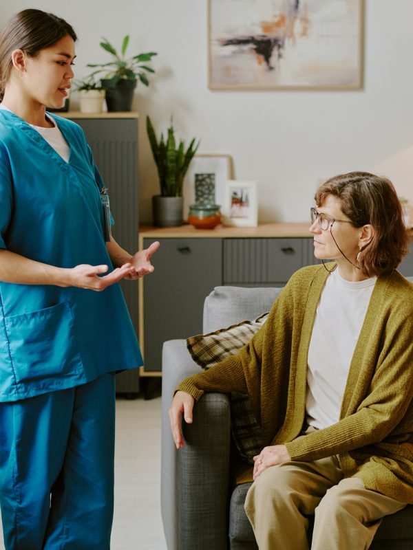 Nurse Consulting Senior Patient in Living Room