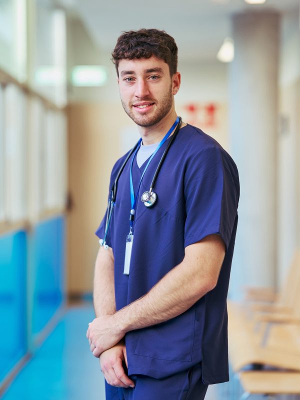 Young male nurse smiling in hospital corridor